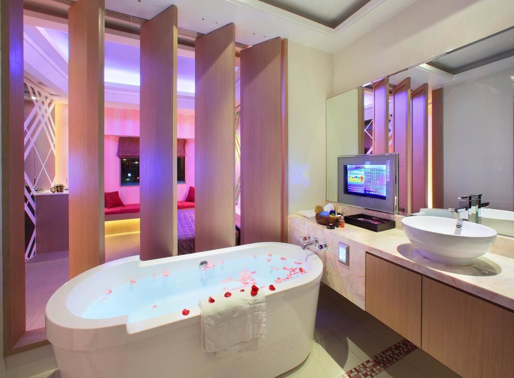 Ein modernes Badezimmer mit einer freistehenden Badewanne, einem großen Spiegel, einem Waschtisch und einem an der Wand montierten Fernseher.