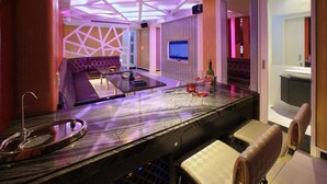 A modern bar area with a marble countertop, seating, and a TV screen. - Roman Vacation Motel (Taichung)