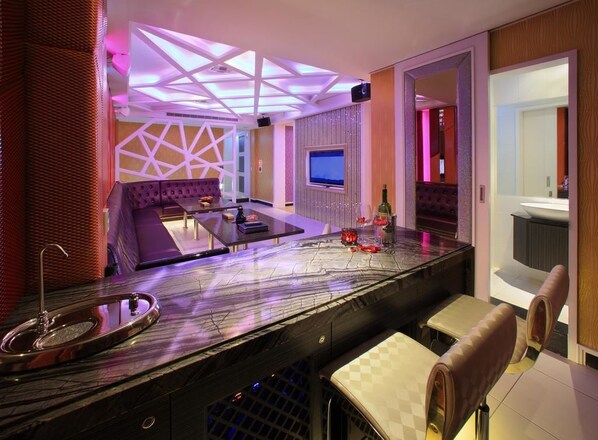 A modern bar area with a marble countertop, seating, and a TV screen. - Roman Vacation Motel (Taichung)