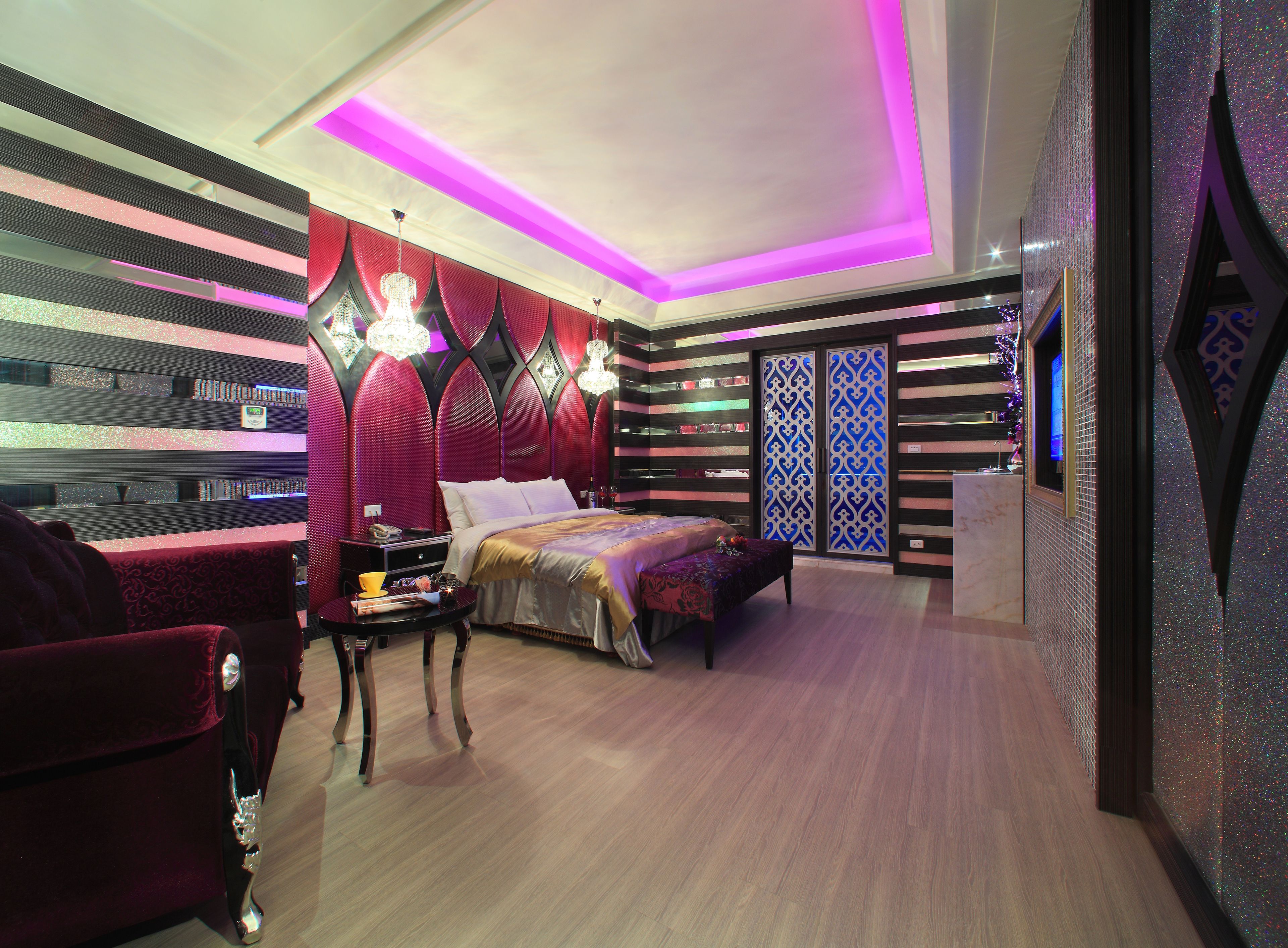 A modern bedroom with a bed, a nightstand, and a red armchair.