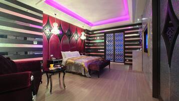 A modern bedroom with a bed, a nightstand, and a red armchair.