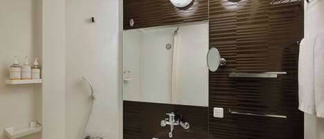 A modern bathroom with a white sink, a large mirror, and a shower area.
