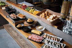 Un bufé con una variedad de alimentos, incluyendo carnes, quesos y frutas.