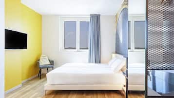 Una habitación de hotel con una cama, un escritorio, una silla, un televisor y una ventana con cortinas.