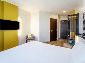 A hotel room with a bed, a chair, a wardrobe, a door, and a shower area. - B&B Hotel Roma Fiumicino Aeroporto Fiera 1 (Fiumicino)