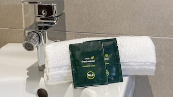 Ein Waschtisch mit Spender für Handtücher, der eine grüne Packung mit der Aufschrift 'Hello Freshness! Intimate Wash' von B&B Hotels enthält.