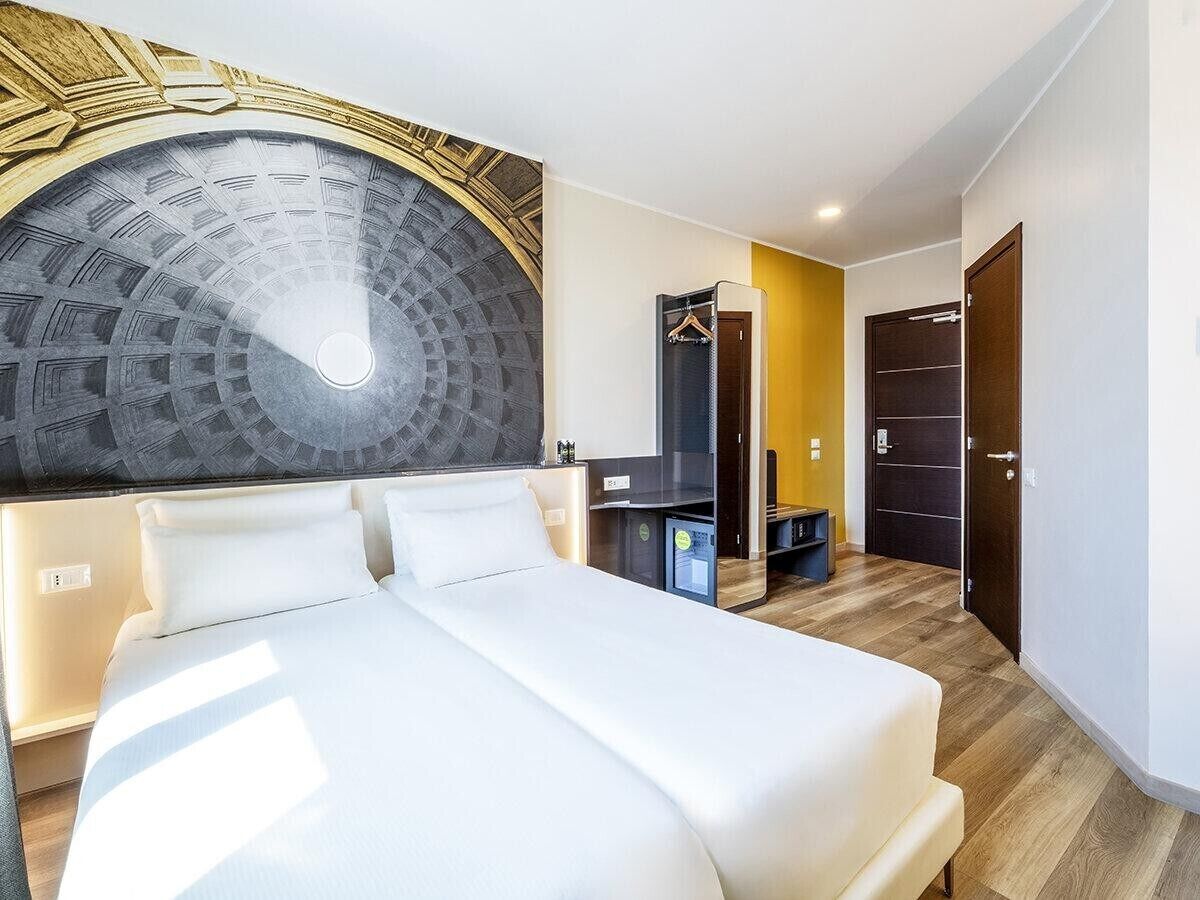 A hotel room with a large bed, a wardrobe, and a mirror.