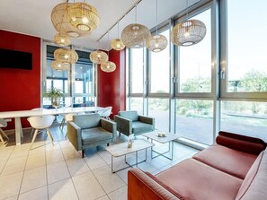 Un intérieur moderne comprenant un coin repas, des canapés et de grandes fenêtres.