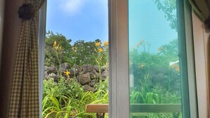 Una ventana con vistas a un jardín, un banco de madera y una mesa.