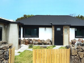 A modern house with a black roof, white walls, and a wooden gate. - Doldam House (Jeju City)
