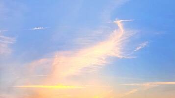 A sunset sky with a few clouds and power lines.