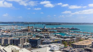 Un paisaje urbano costero con un puerto deportivo, edificios modernos y un puente en la distancia.