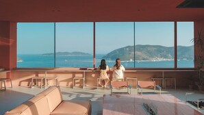 A spacious room with large windows offering a view of the sea and hills. There are several seating areas with tables and chairs. - Hotel SangSang & Private SangSang Pool Villa  (Geoje)