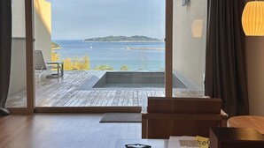 A modern room with a large sliding glass door leading to a balcony with a view of the sea. - Hotel SangSang & Private SangSang Pool Villa  (Geoje)