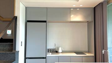 Una cocina moderna con refrigerador empotrado, hervidor y pileta.