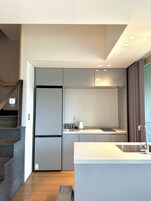 Una cocina moderna con refrigerador empotrado, hervidor y pileta.