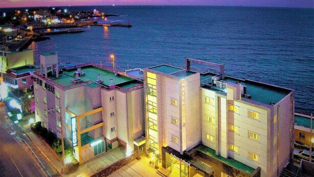 A hotel with a rooftop terrace, multiple floors, and a view of the sea. - Fantastic Ocean View Sydney Hotel (Jeju City)