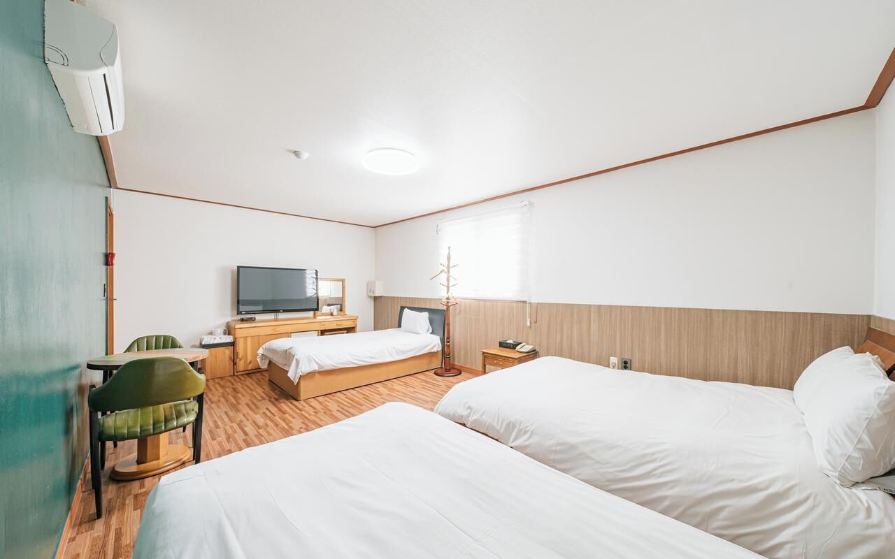 Une chambre d’hôtel avec deux lits, une télévision, un bureau et une chaise.