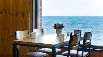 A wooden table with four chairs, a vase with flowers, and a framed picture.