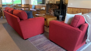 Un salon chaleureux avec un canapé rouge, une table basse en bois et une cheminée en pierre.