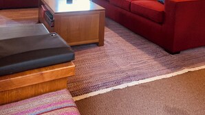 Un salon chaleureux avec deux canapés rouges, une table basse en bois et un tapis à motifs.