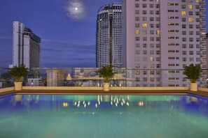 A rooftop pool with a city skyline view, including high-rise buildings and a moon in the sky. - Sata Hotel (Nha Trang)