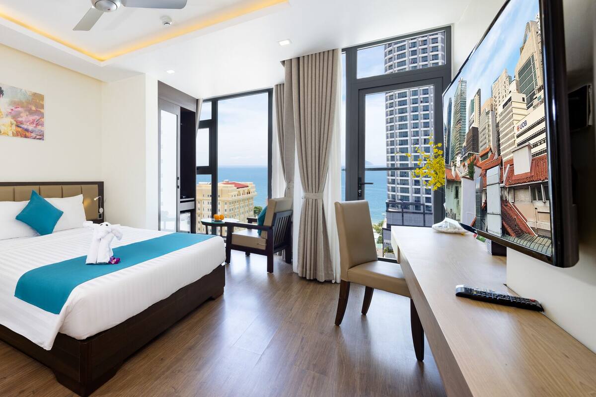 Une chambre d’hôtel avec un grand lit, un bureau, une chaise et une vue sur la ville.