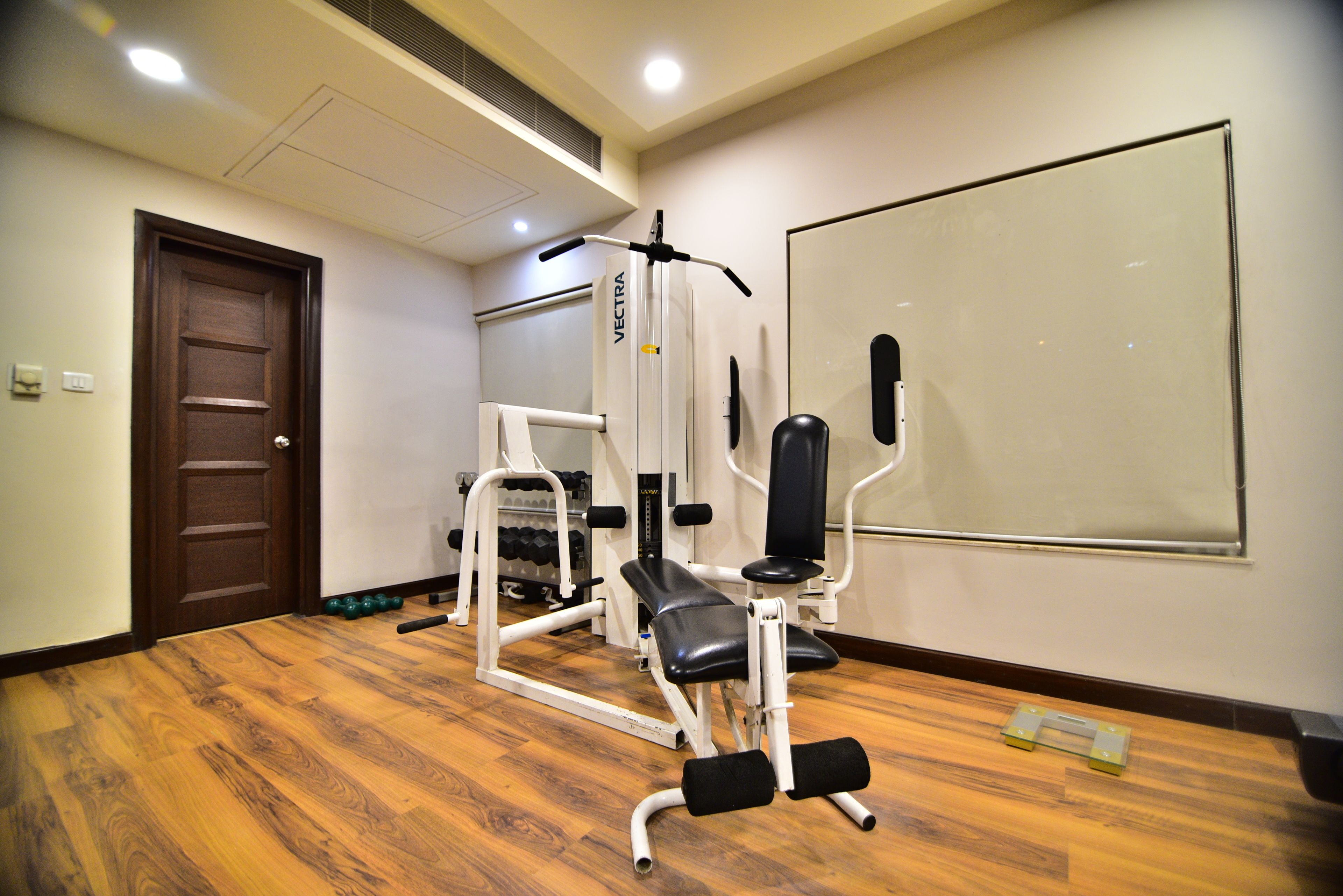 A gym with exercise equipment, a door, and a whiteboard on the wall.