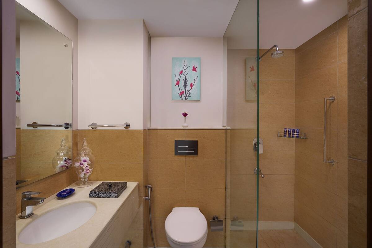 Un baño con lavamanos, inodoro, ducha y cabina de ducha con paredes de vidrio.