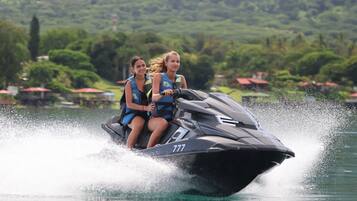 Two people on a jet ski with a number 777, surrounded by water and greenery.