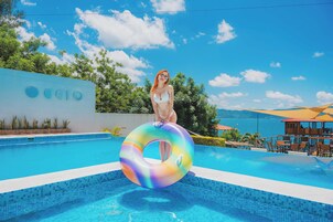 Una piscina al aire libre, sombrillas, sillones reclinables de piscina