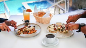 Una mesa con platos de comida, un cesto de pan, una bebida y una taza de café.