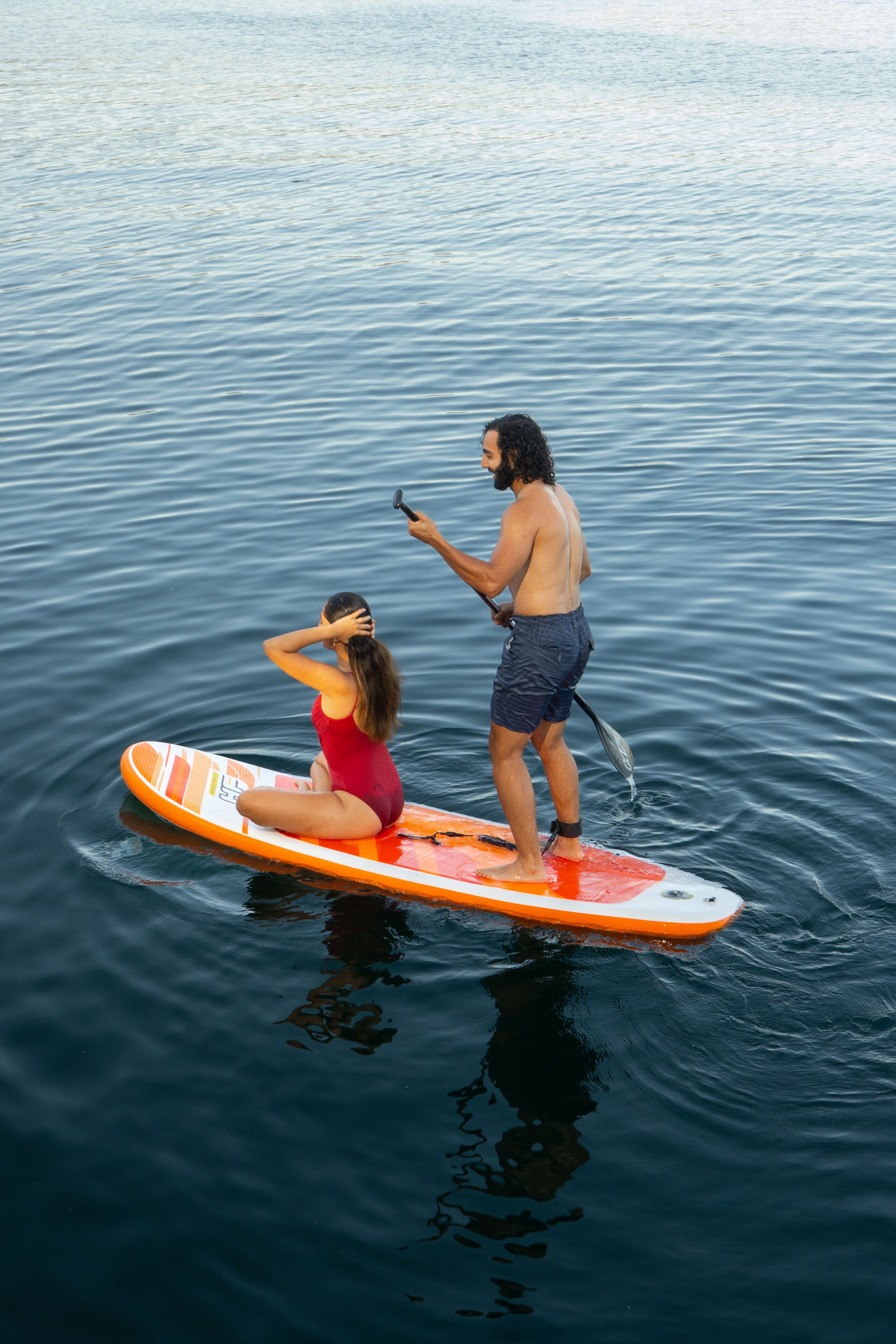 Two people on a paddleboard in calm water.