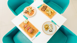 A table with four plates of food, each labeled with a name. - Equinoccio Hotel (Santa Ana)