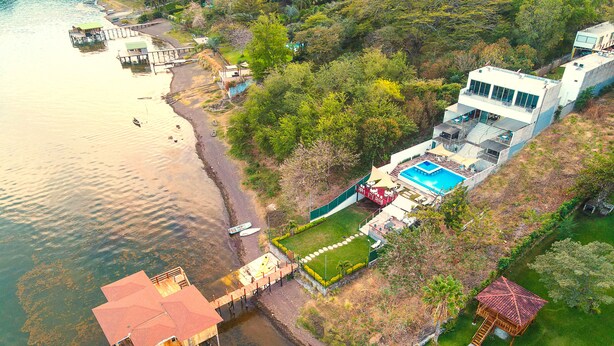 Propiedad costera con piscina, muelle y un pequeño bote.