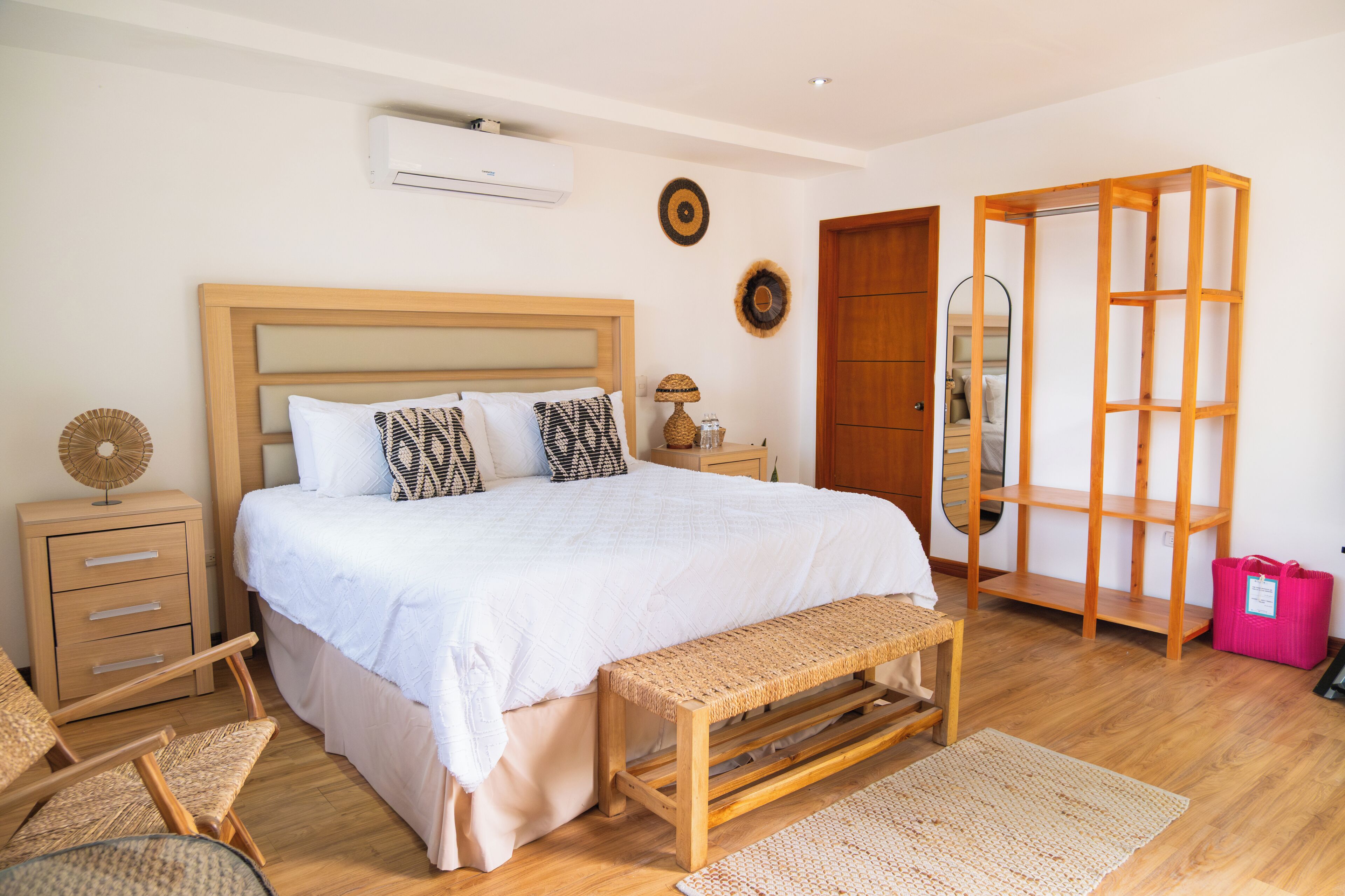 A bedroom with a wooden bed, bedside tables, a bench, and a wardrobe.