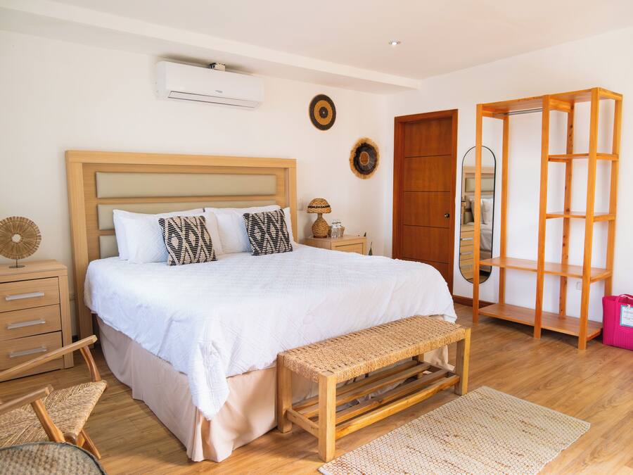 A bedroom with a wooden bed, bedside tables, a bench, and a wardrobe.