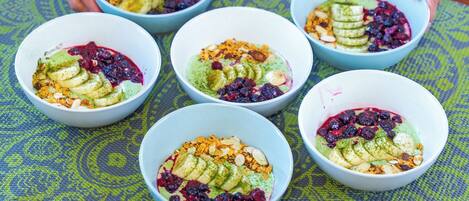 A person arranging bowls of food on a patterned mat.