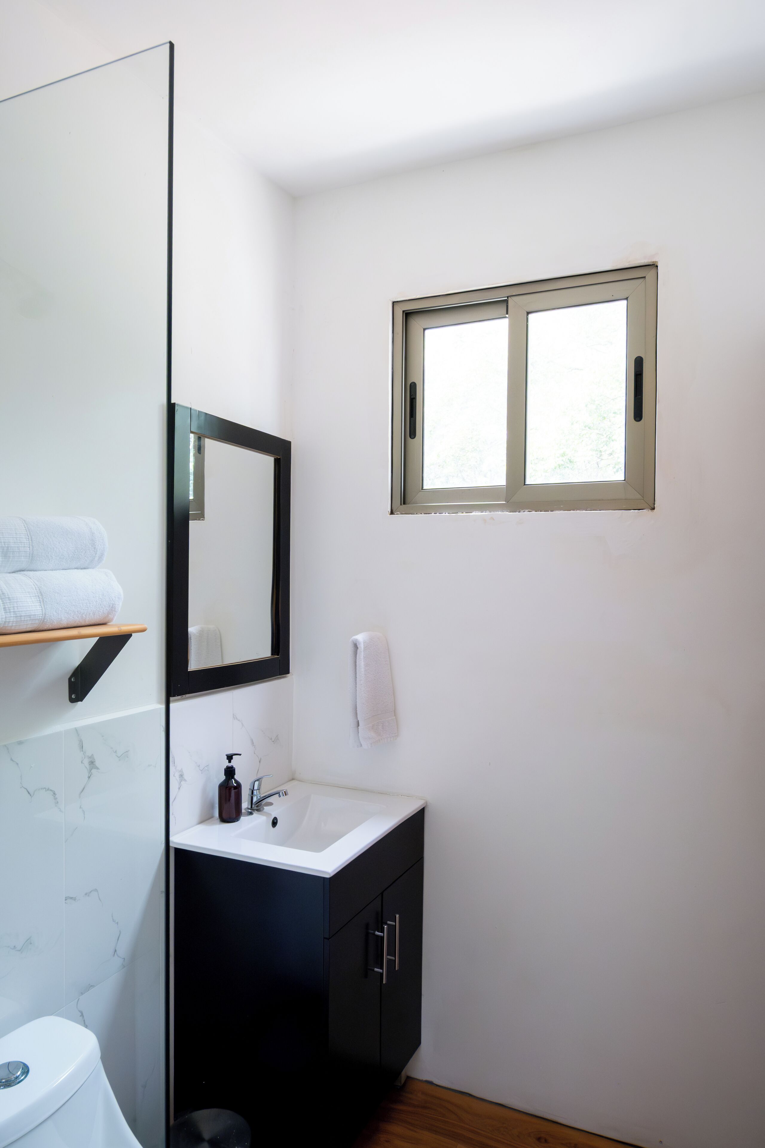 Une salle de bain avec des toilettes, un lavabo, un miroir et une fenêtre.