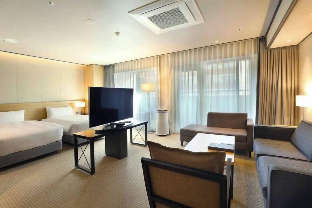 Een hotelkamer met een bed, een televisie, een bureau, een stoel en een bank.