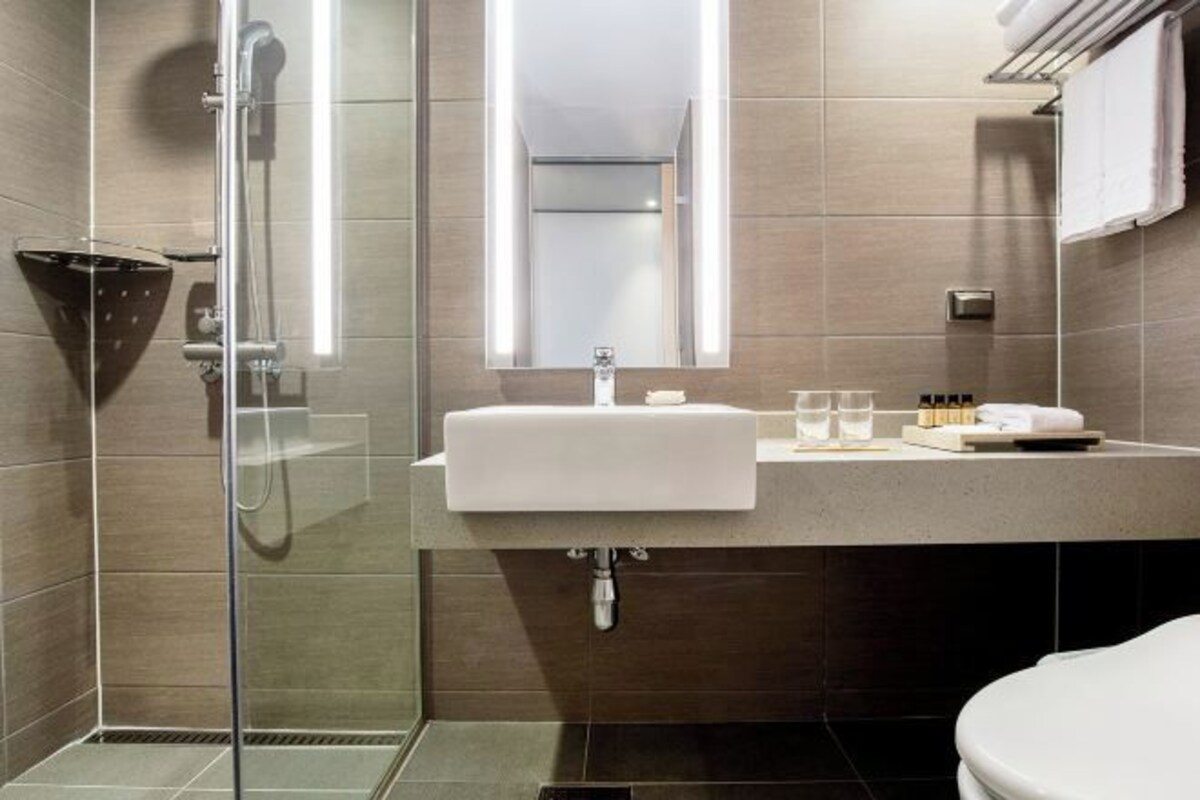 A modern bathroom with a glass-enclosed shower, a white sink, and a mirror above it.