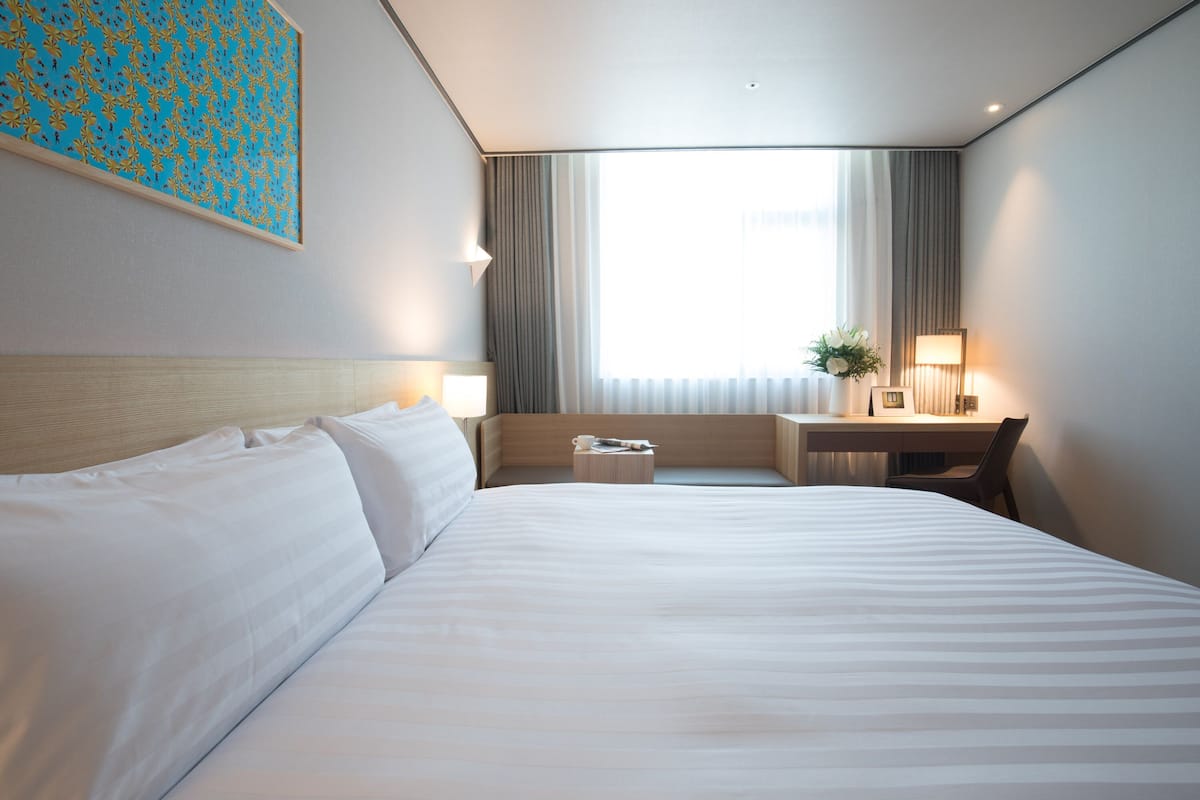 Une chambre d’hôtel avec un grand lit, un bureau et une chaise.