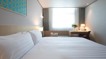 A hotel room with a large bed, a desk, and a chair.