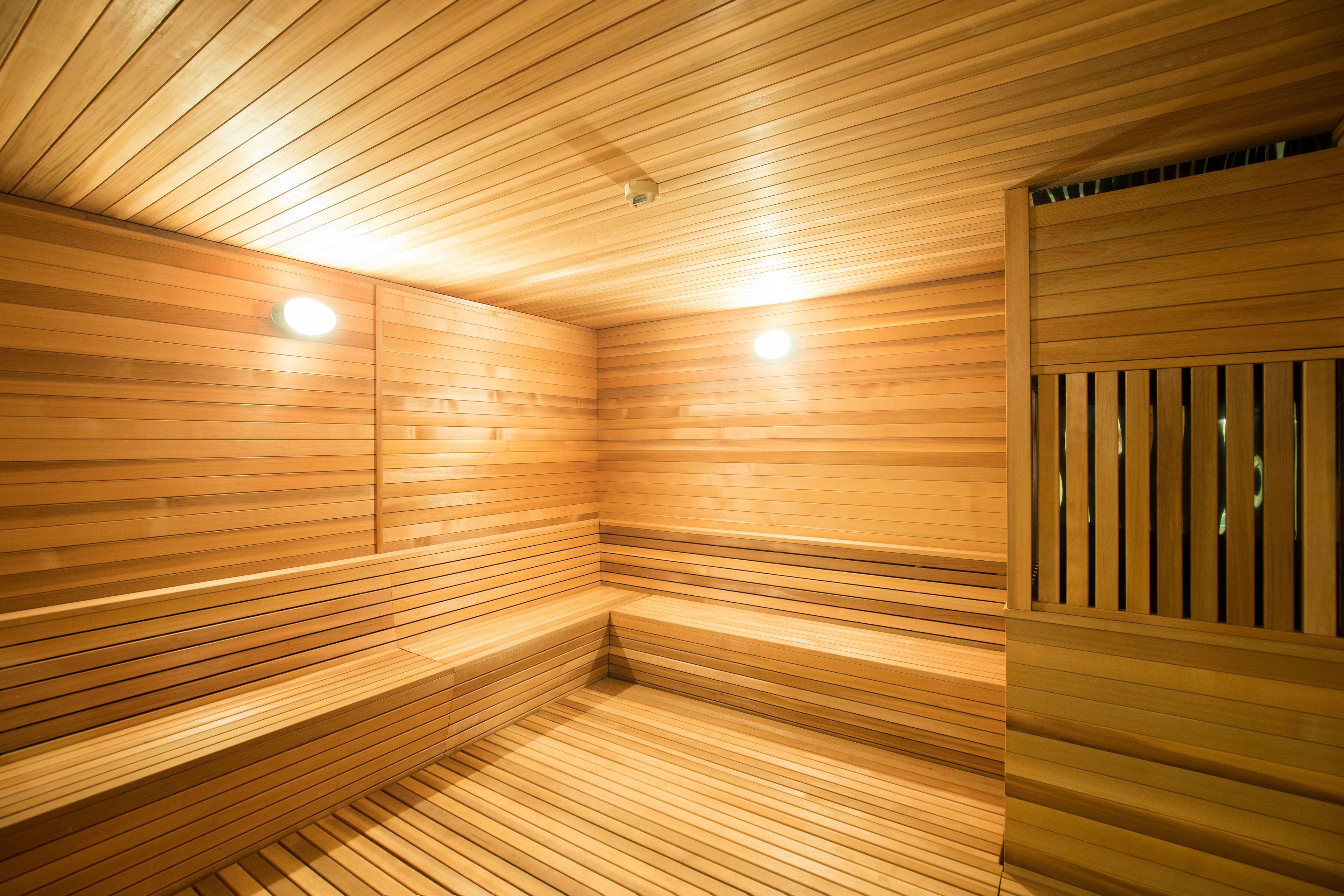 A sauna with wooden slats on the walls and ceiling, and benches along the walls.