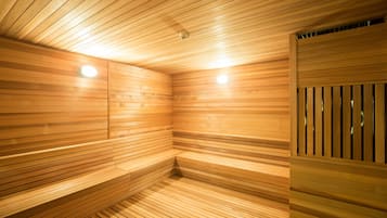 A sauna with wooden slats on the walls and ceiling, and benches along the walls.
