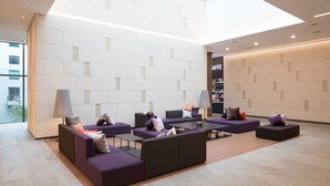 A modern lobby with purple sofas, a coffee bar, and a large window.