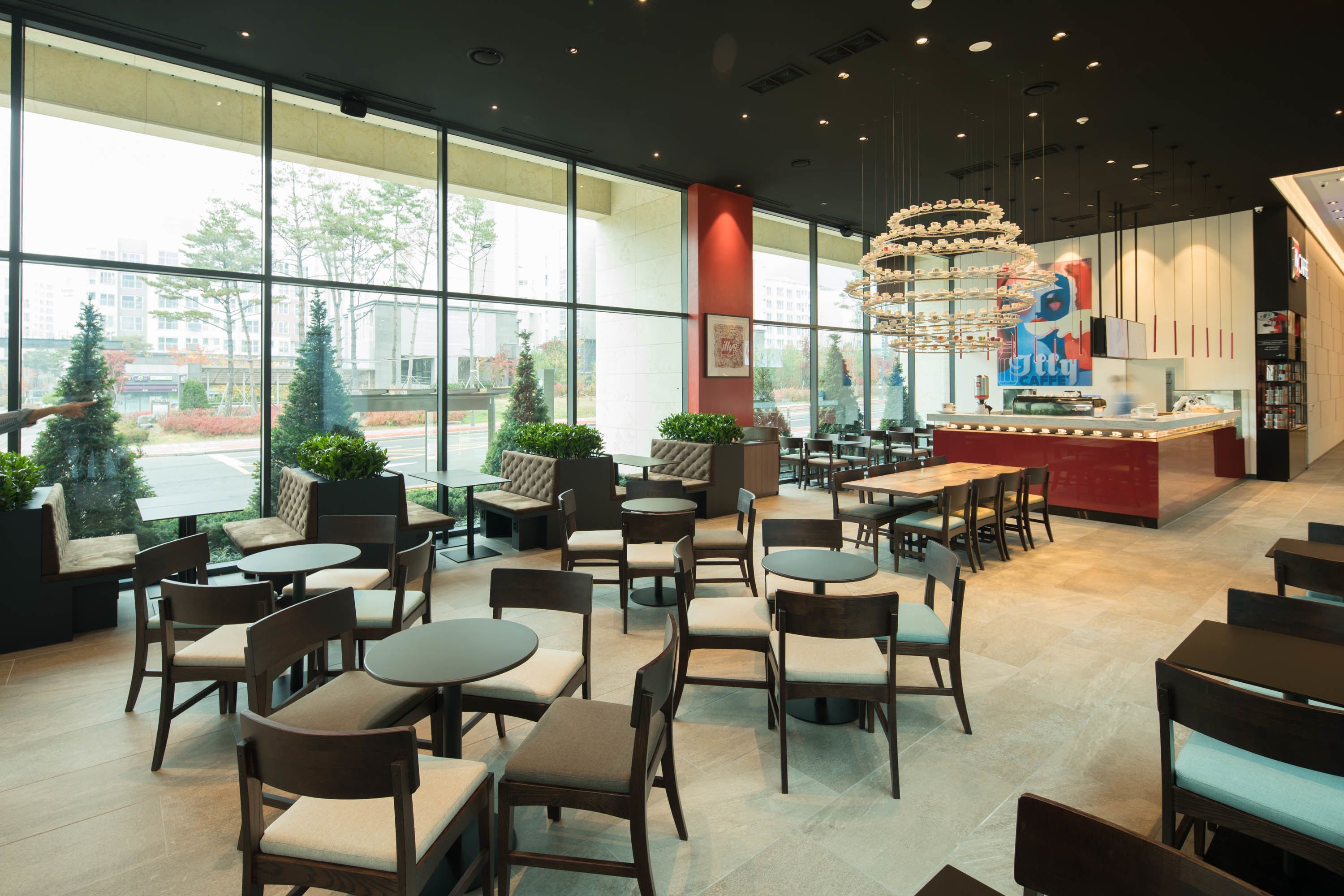 Un espace intérieur spacieux avec de nombreuses tables et chaises, de grandes fenêtres donnant sur l’extérieur et un comptoir central agrémenté d’une enseigne.