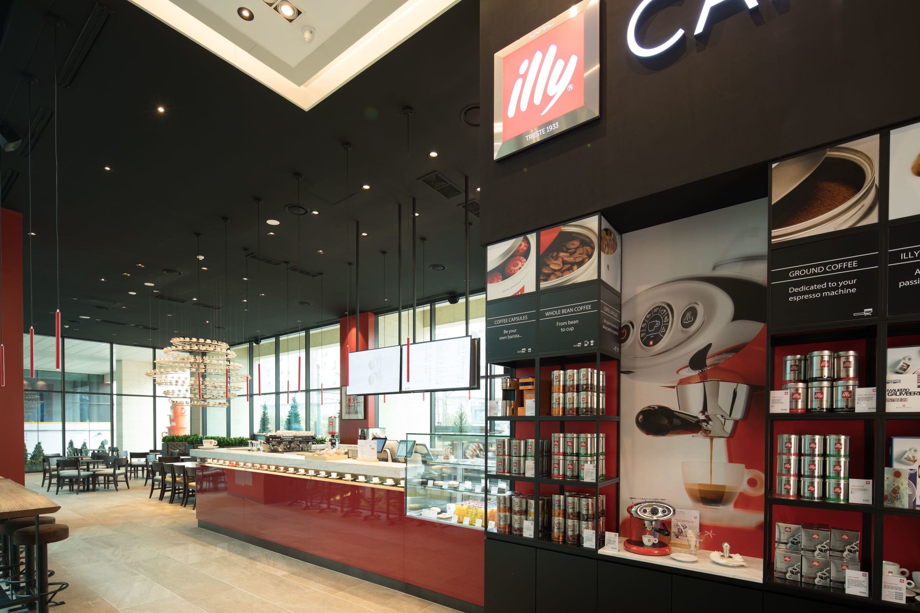 A modern coffee shop interior with a counter, seating area, and display of coffee products.