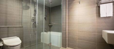 A modern bathroom with a glass-enclosed shower, a toilet, and a bathtub.