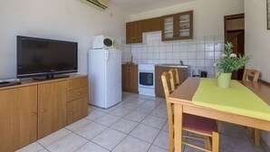 A compact kitchen with a TV, refrigerator, microwave, and a dining area with a table and chairs.